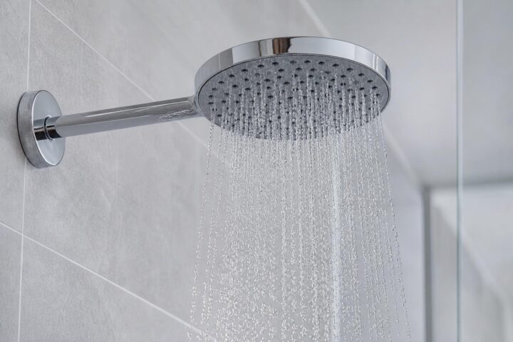 Moderner runder Chrom-Duschkopf mit gleichmäßigem Wasserstrahl in einer hell gefliesten Dusche